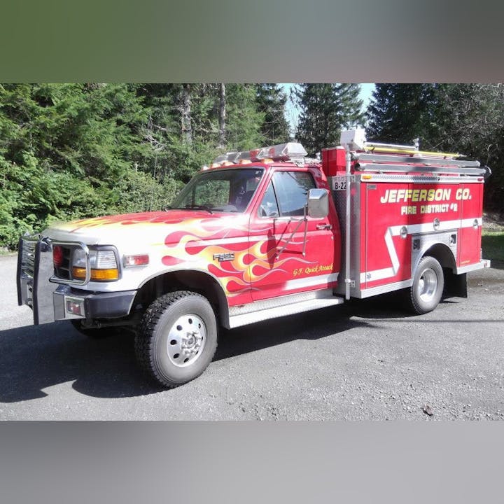 A red fire truck with flame decals, marked as "Jefferson Co. Fire District #2," parked in a forested area.