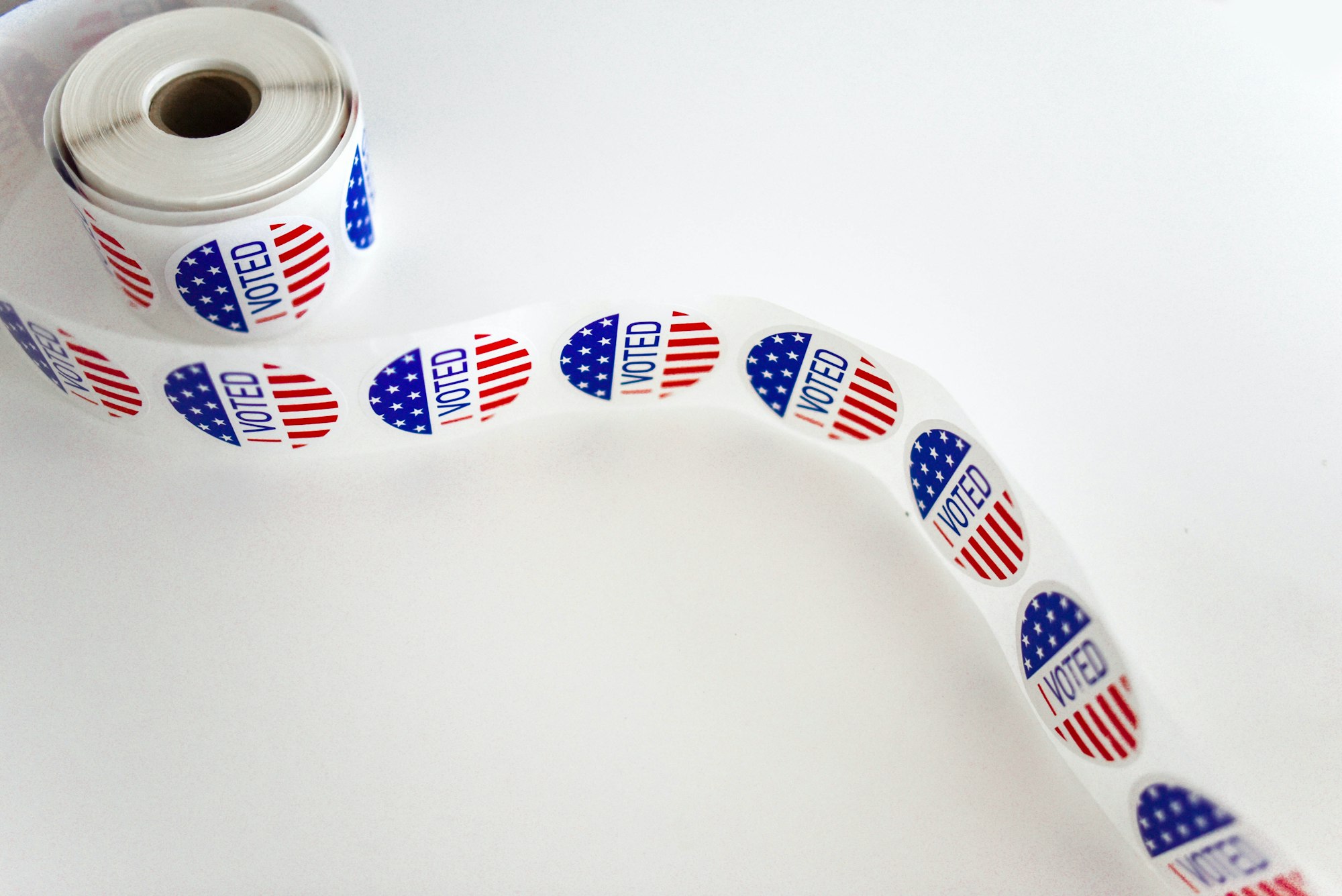 Roll of stickers that read "voted" with American flag design on them
