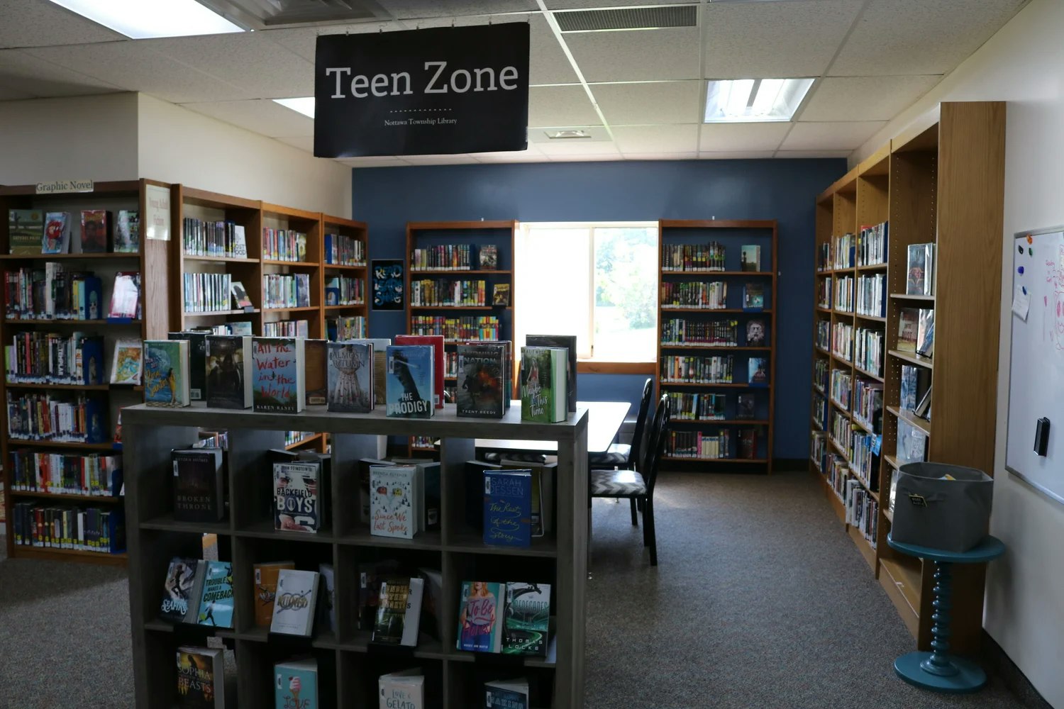 Library Teen Zone with bookshelves, tables, and chairs.