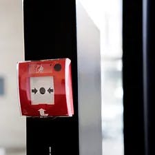 Red fire alarm pull station on a wall.