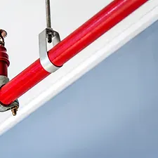 A close-up of a red heating element with metal clamps against a light blue background.