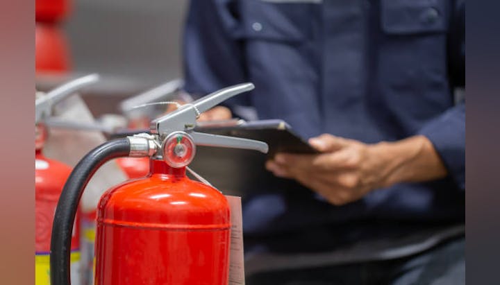 Picture of someone inspecting a fire extinguisher