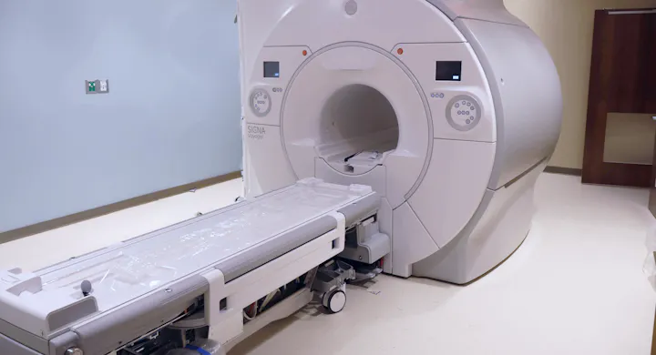 An MRI machine in a medical room with a patient table ready for scanning.