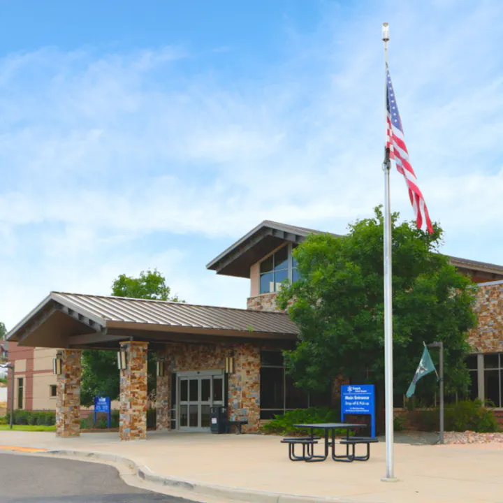 A modern building with an American flag and a bench outside.