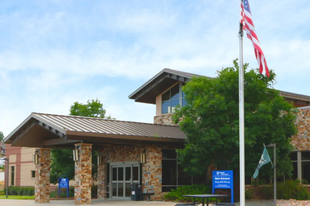 A modern building with an American flag and a bench outside.