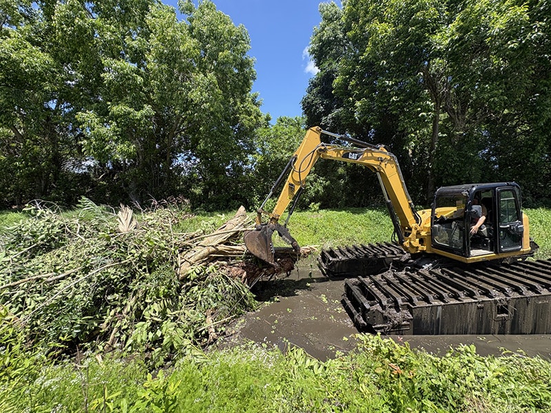 An amphibious excavator removing vegetative storm debris from Canal 3 in Jupiter Farms in South Indian River Water Control District.