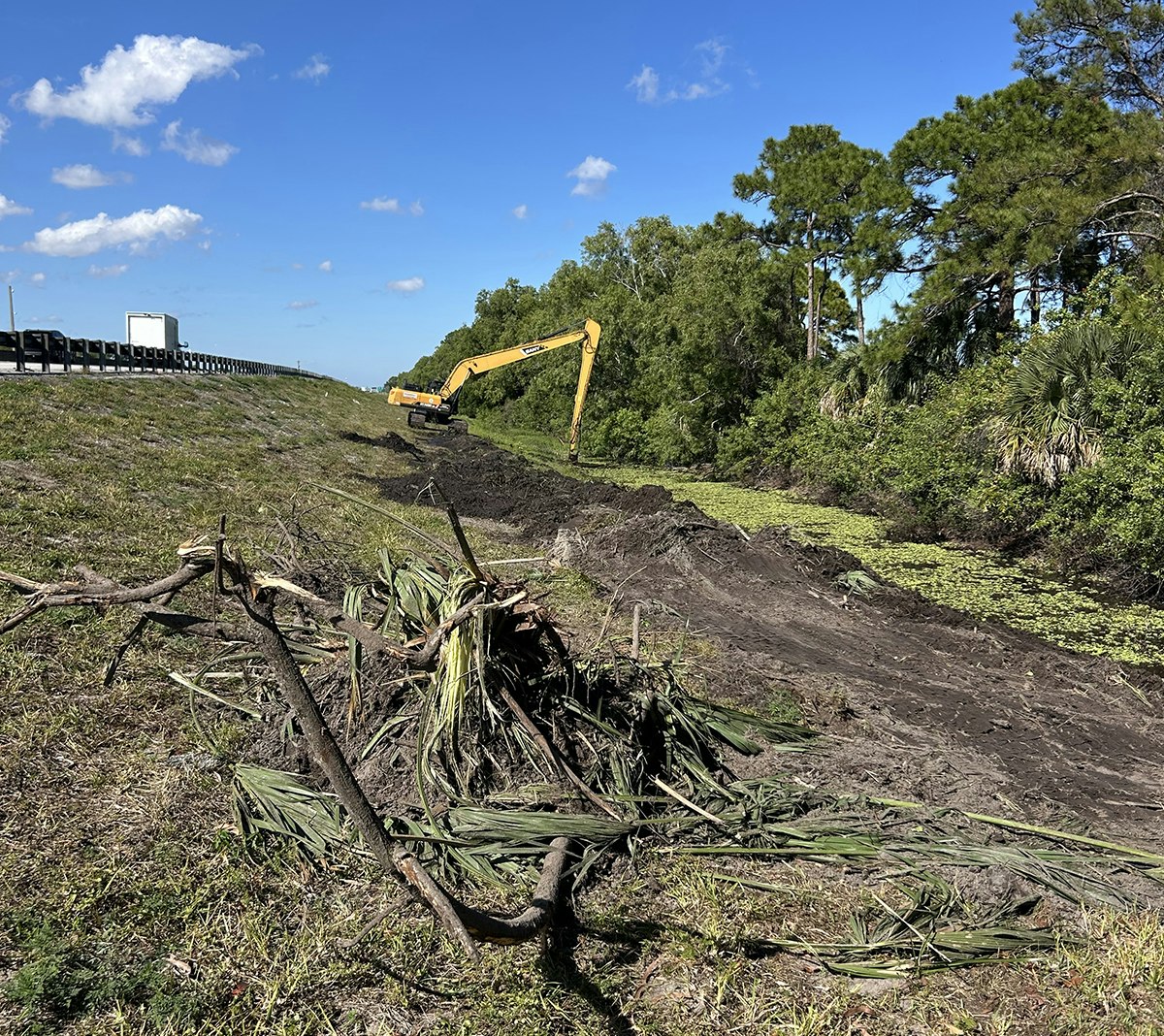 An excavator is clearing trees and vegetation alongside the Turnpike's East Borrow Canal to improve water flow.