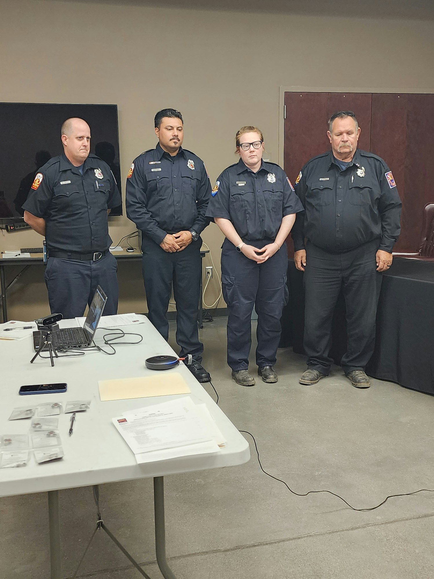 May contain: officer, person, police officer, wristwatch, adult, male, man, clothing, footwear, shoe, accessories, glasses, belt, computer, electronics, laptop, pc, pen, desk, furniture, and table