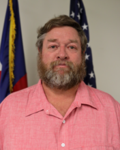 May contain: beard, face, head, person, adult, male, man, and flag