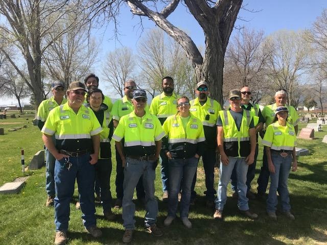 A group of people in safety vests posing for a photo outdoors.