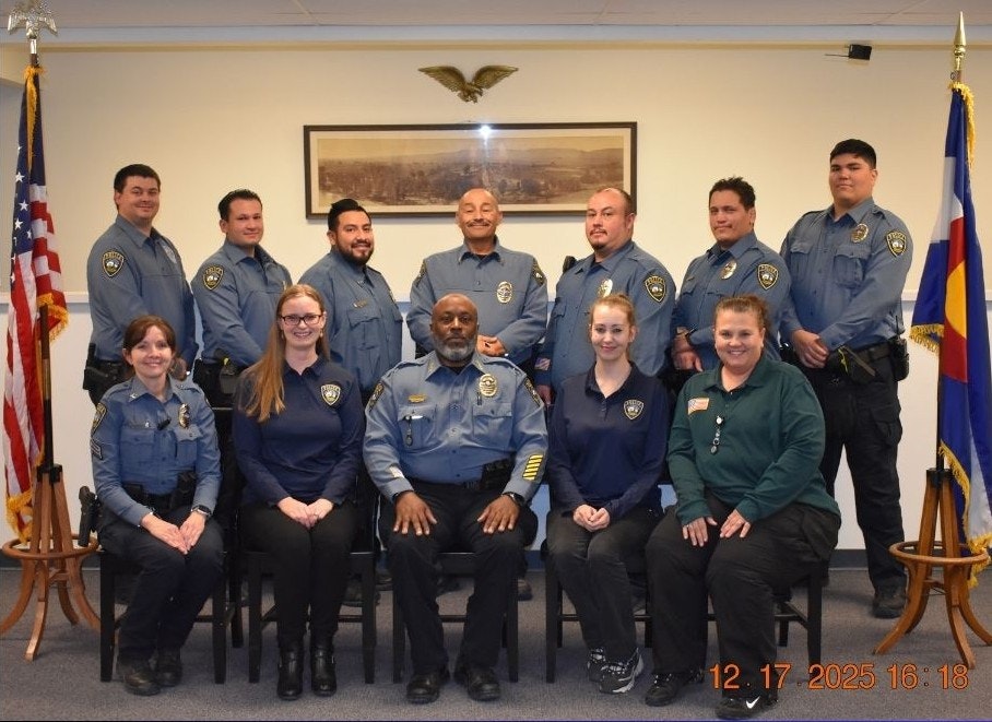A group photo of police officers and staff in uniform, posing indoors with flags in the background.