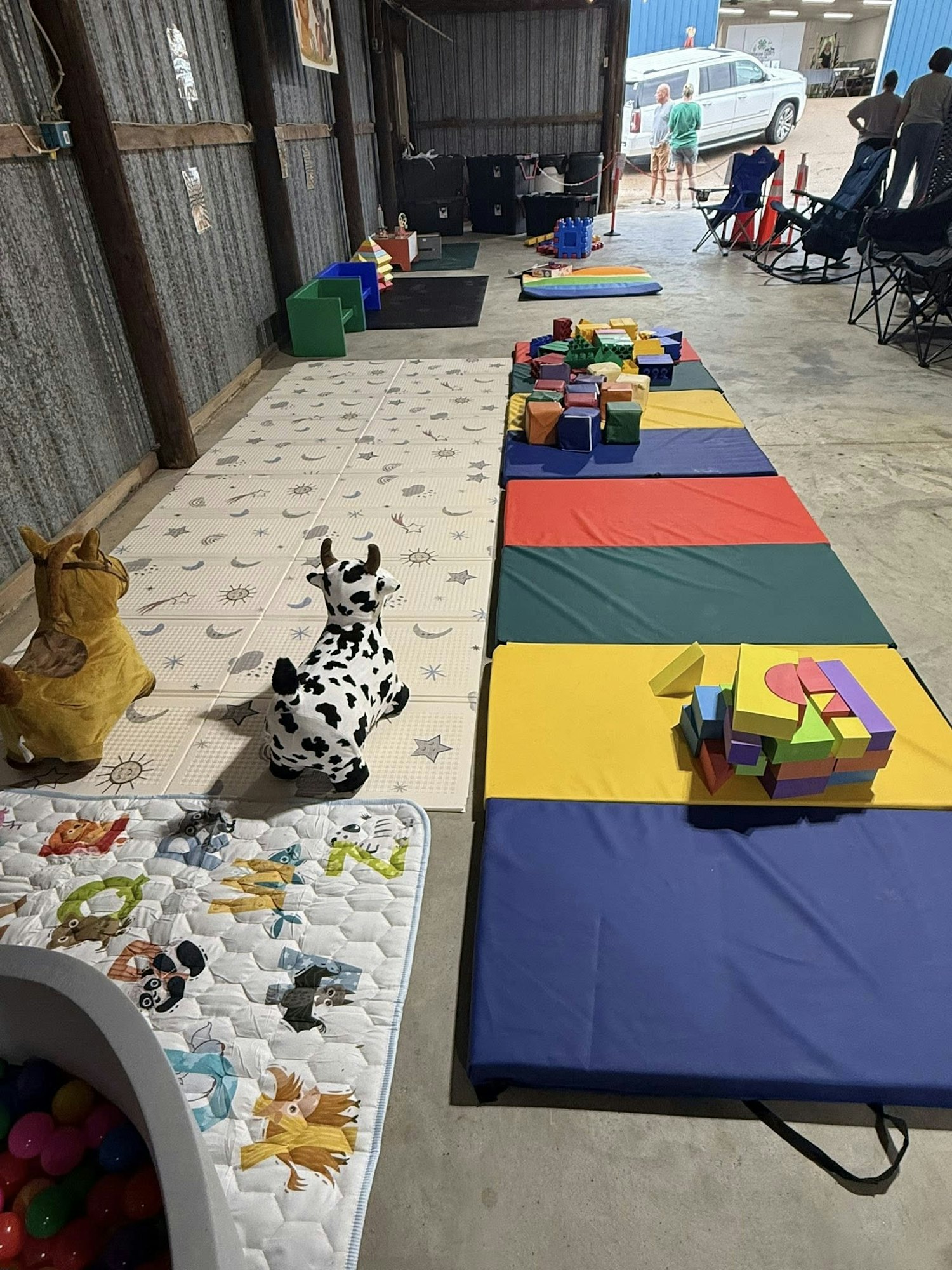 Indoor play area with foam mats, toys, and inflatable animals.