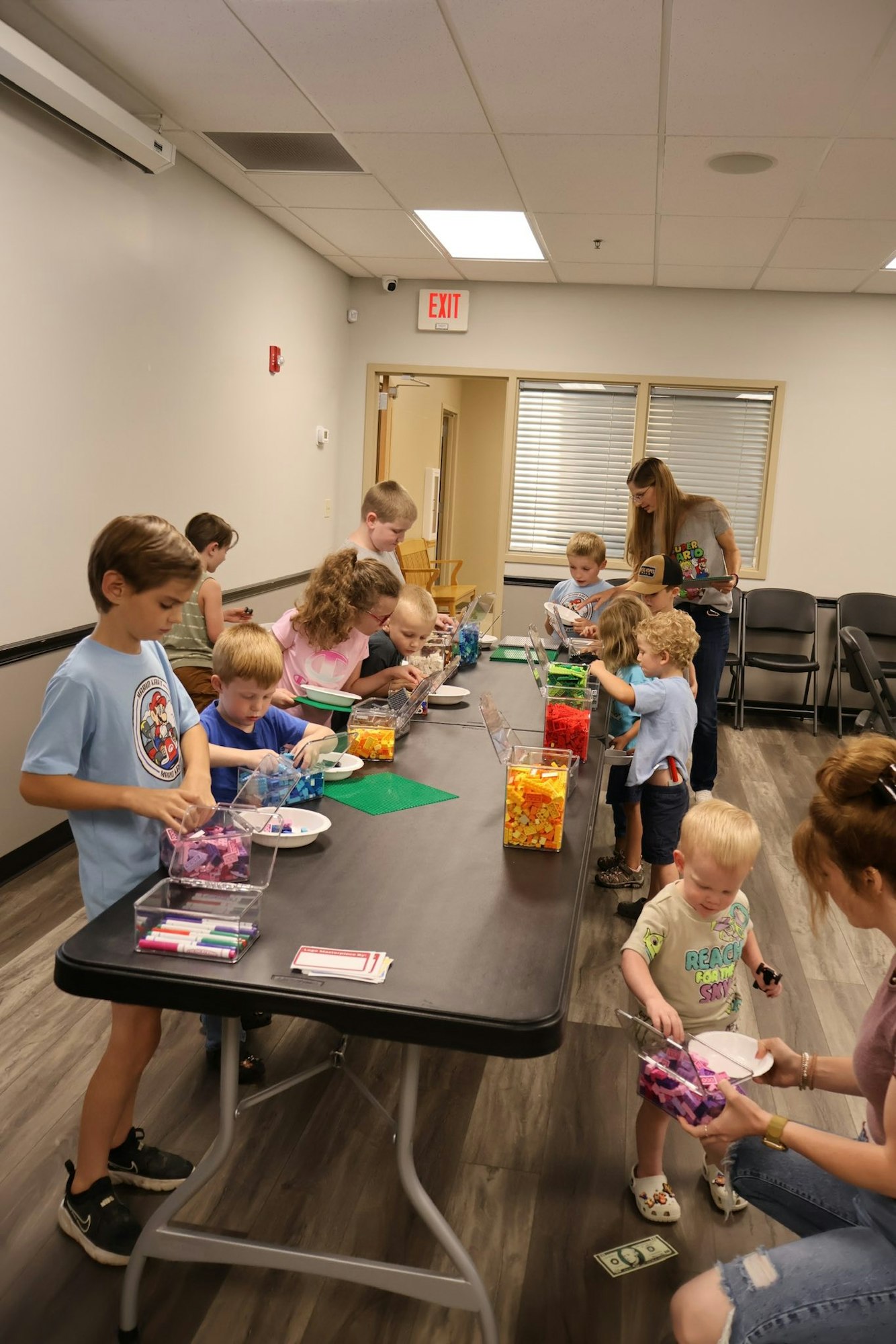 Children at a table engaging in a group activity with colorful building blocks and containers.