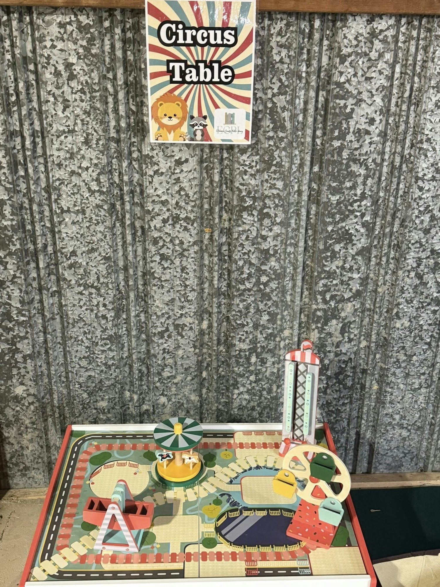 A "Circus Table" setup with miniature amusement park rides on a decorative table against a metal wall.