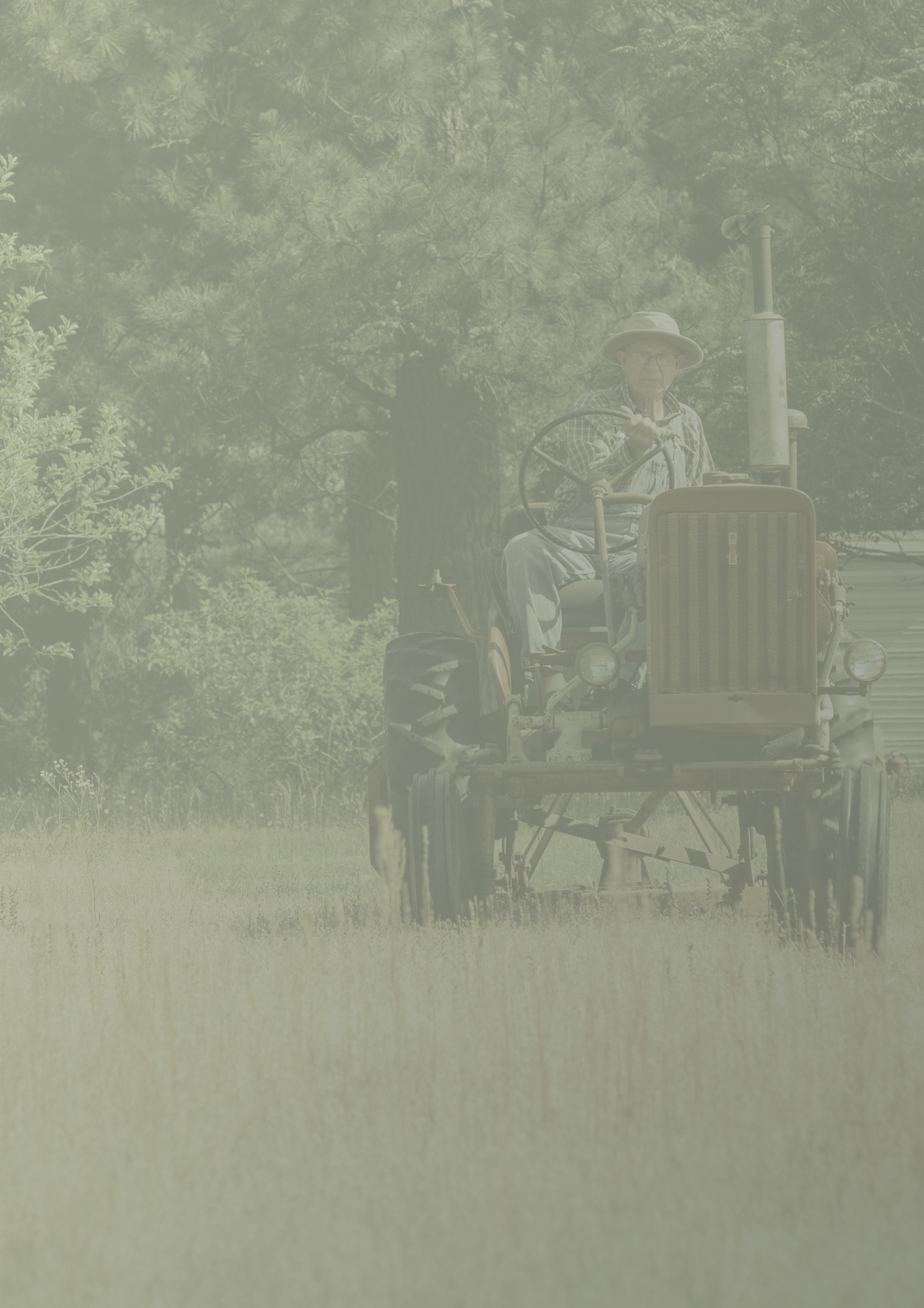 An individual driving a vintage tractor through a field.