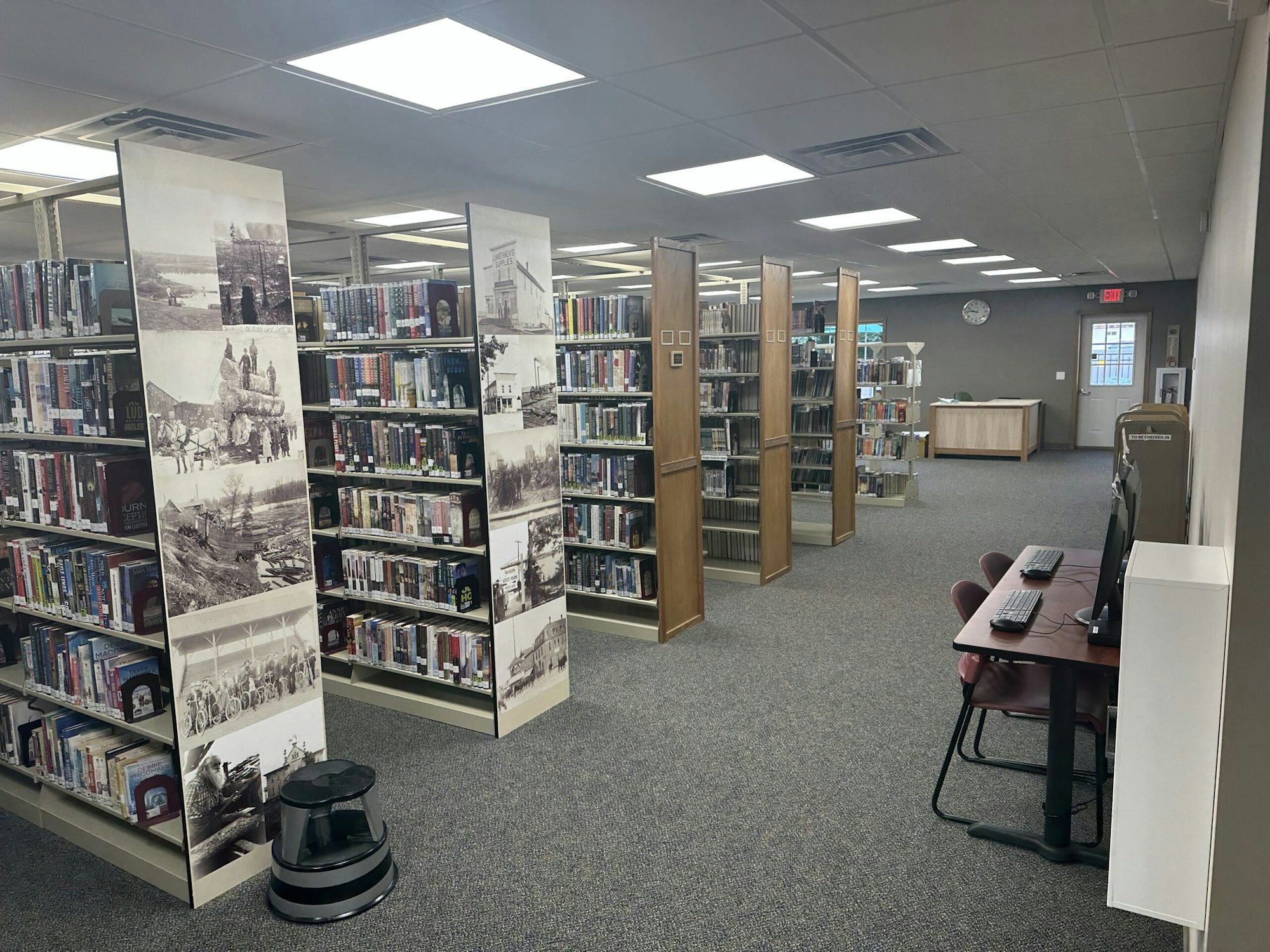 Library interior with bookshelves, vintage photos, a computer station, and seating area.