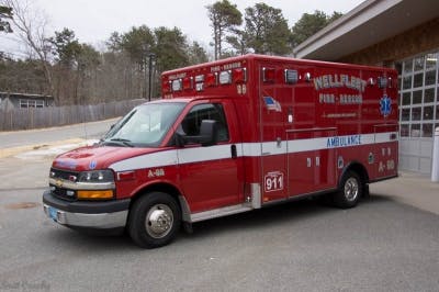 A red ambulance vehicle parked outside a building, marked with "911" and "FIRE-RESCUE" signage.