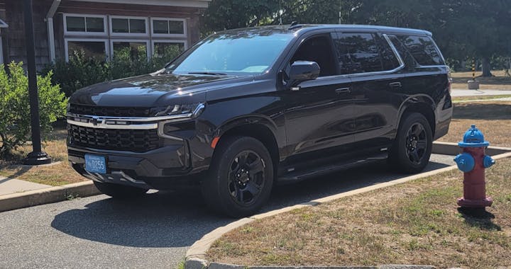 A black SUV parked next to a blue fire hydrant on a sunny day.