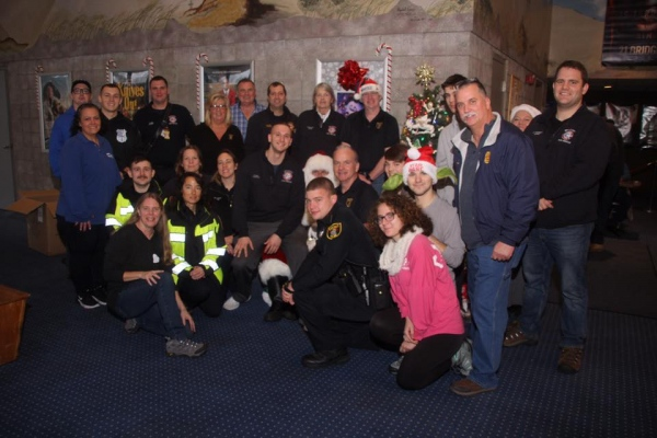 Group of people posing indoors, possibly emergency responders/firefighters, with holiday decorations.