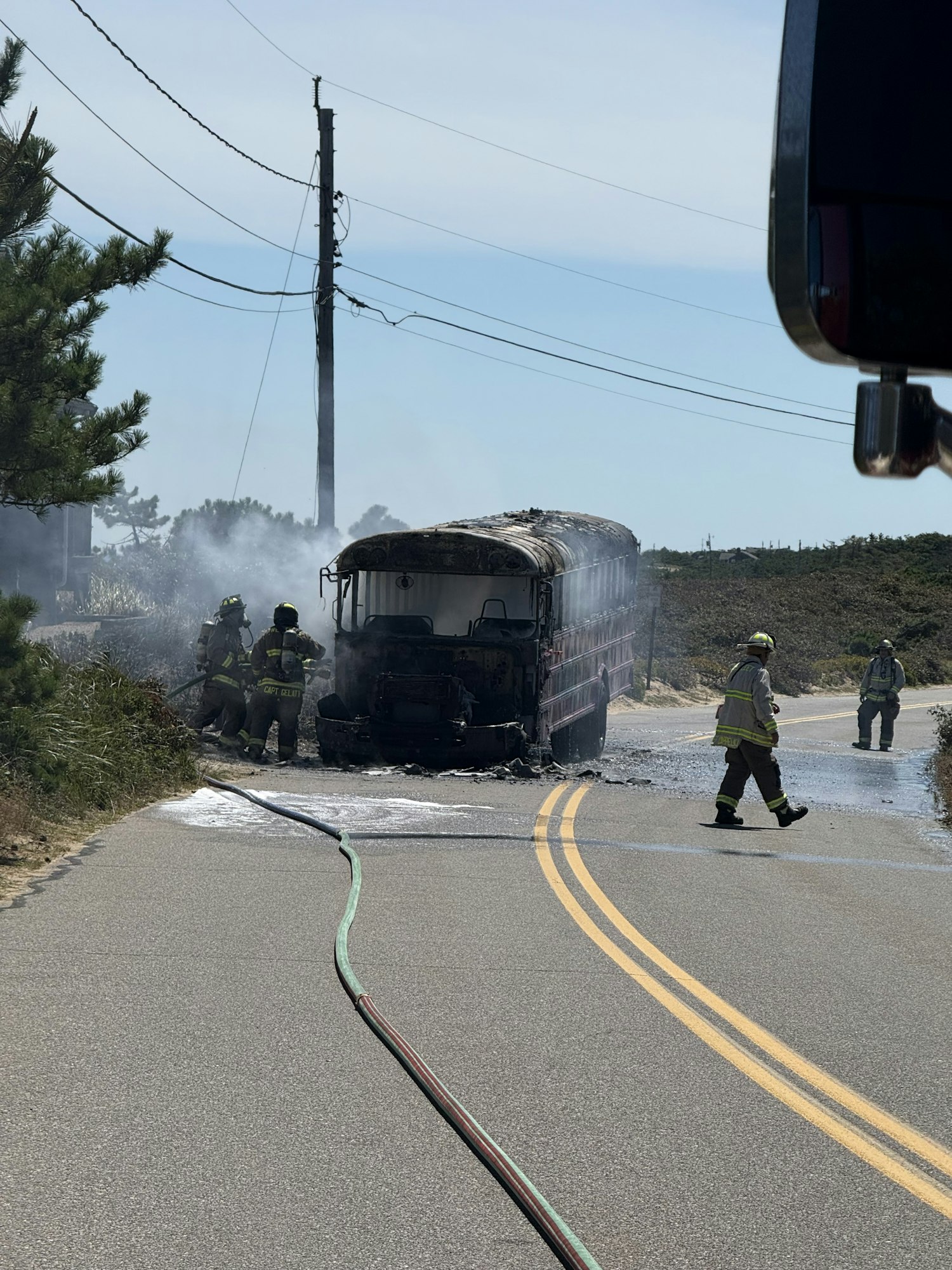 Firefighters extinguishing a fire in a truck on the road using hoses.