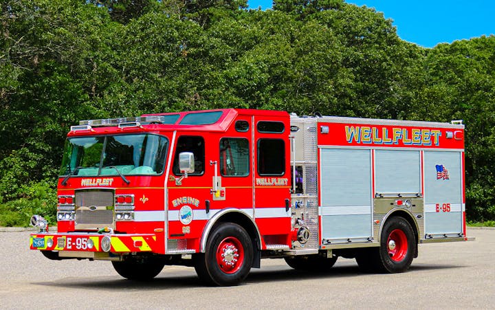 A red Wellfleet fire engine parked with trees in the background.