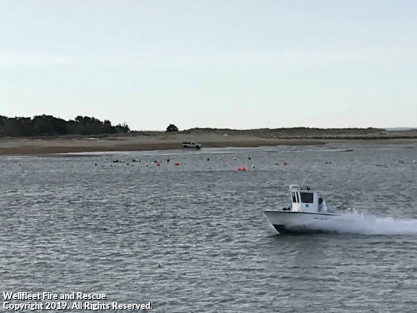 A boat speeding on water with buoys and land in the background.