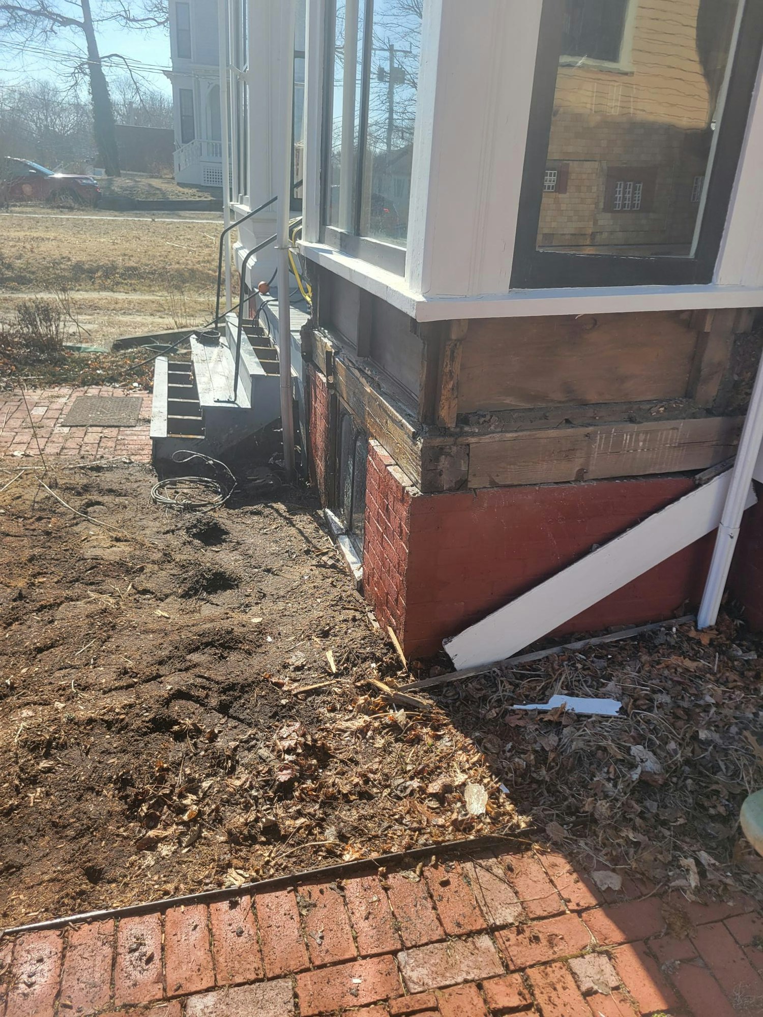 A construction area with exposed bricks, soil, and a partially dismantled section near a window.