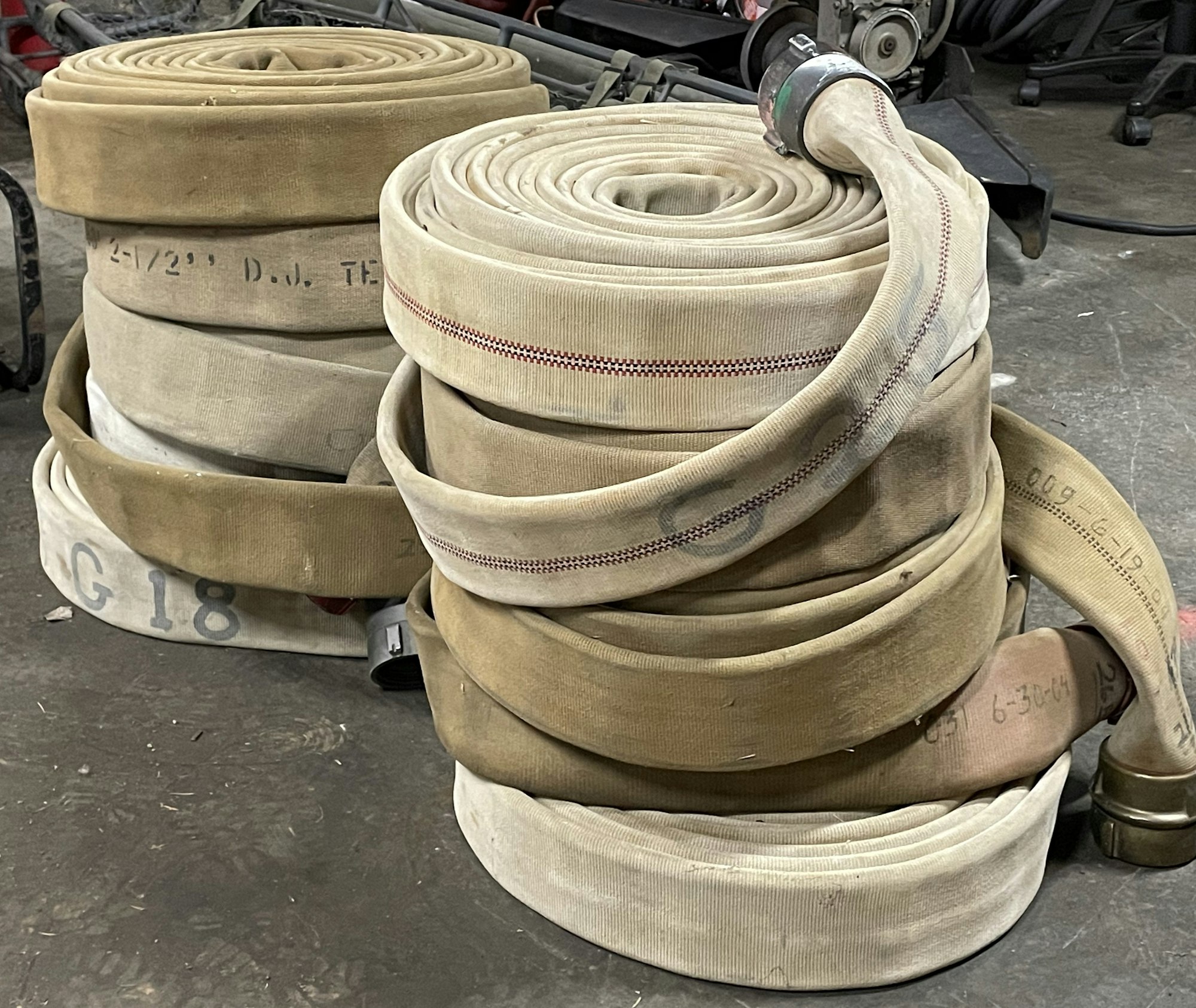 Coiled fire hoses stacked on a concrete floor.