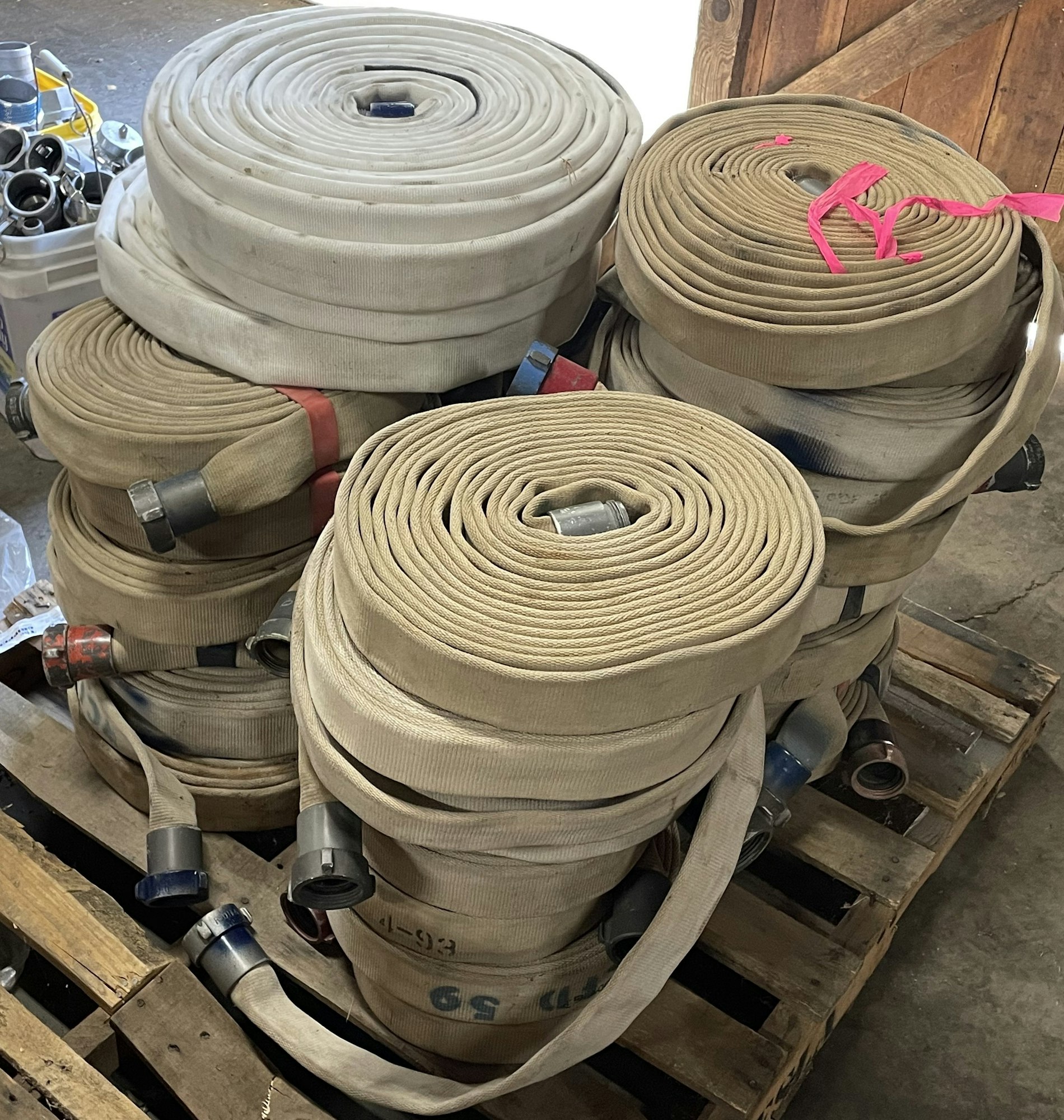 Coiled fire hoses stacked on a wooden pallet.