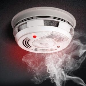 Smoke alarm with smoke and a glowing red light.
