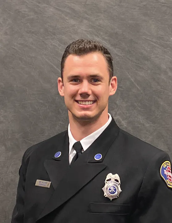 The image features a smiling individual in a formal uniform, likely belonging to a fire or emergency service.