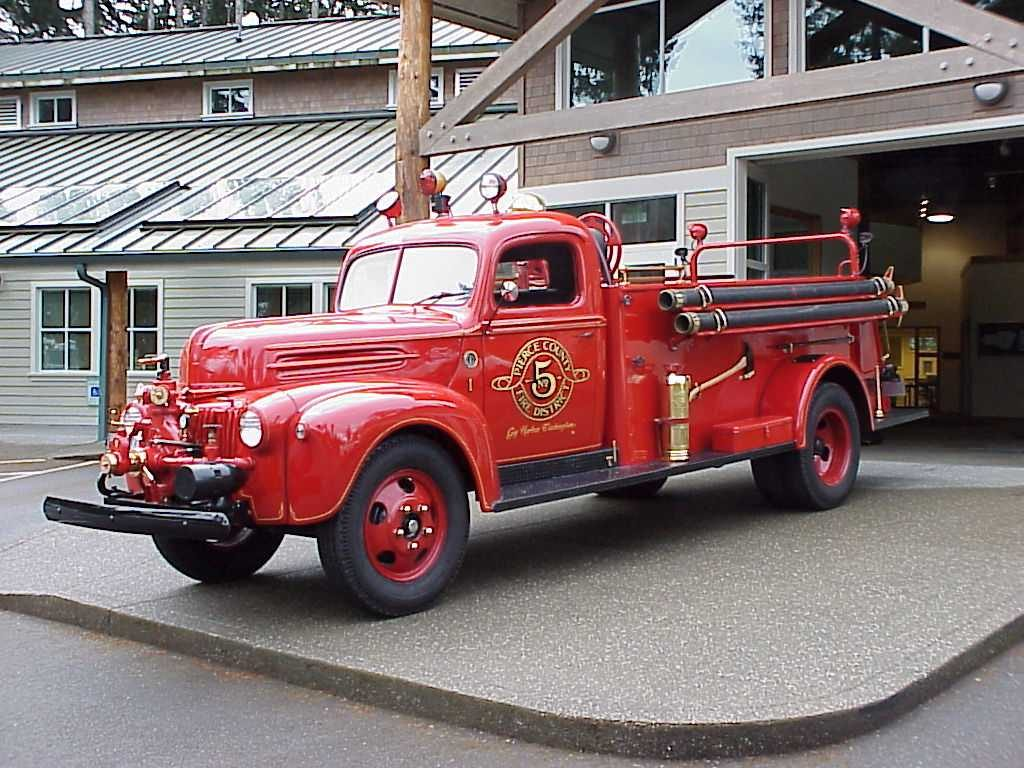 A vintage red fire truck parked outside a building, showcasing classic design and detailing.