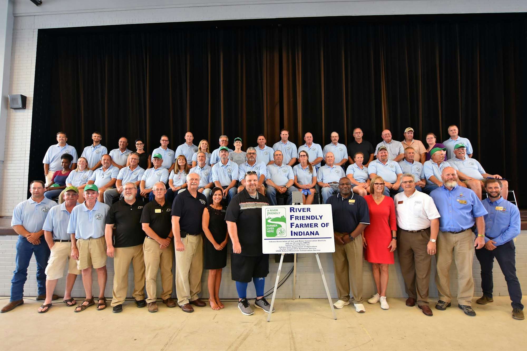A group of people posing with a "River Friendly Farmer of Indiana" sign.