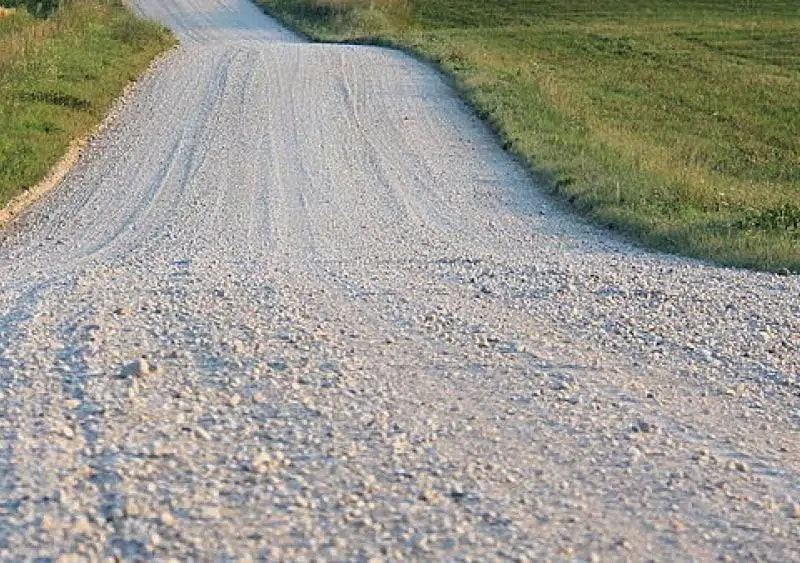 A fork in a gravel road with grass on either side.