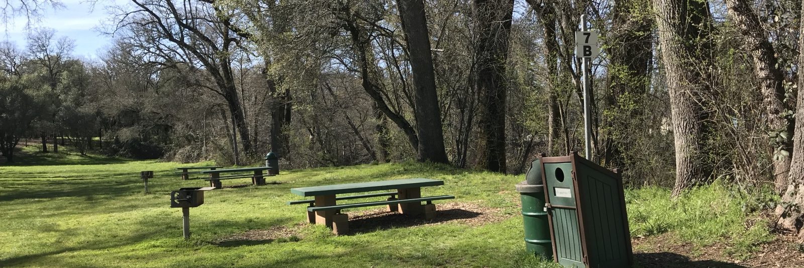 A grassy area with picnic tables, grills, trash bins, and trees, marked "7B."