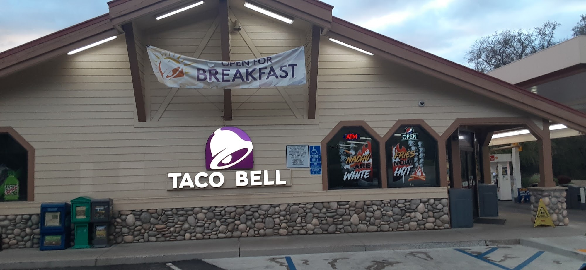 Taco Bell restaurant with a "Open for Breakfast" banner and an ATM sign.