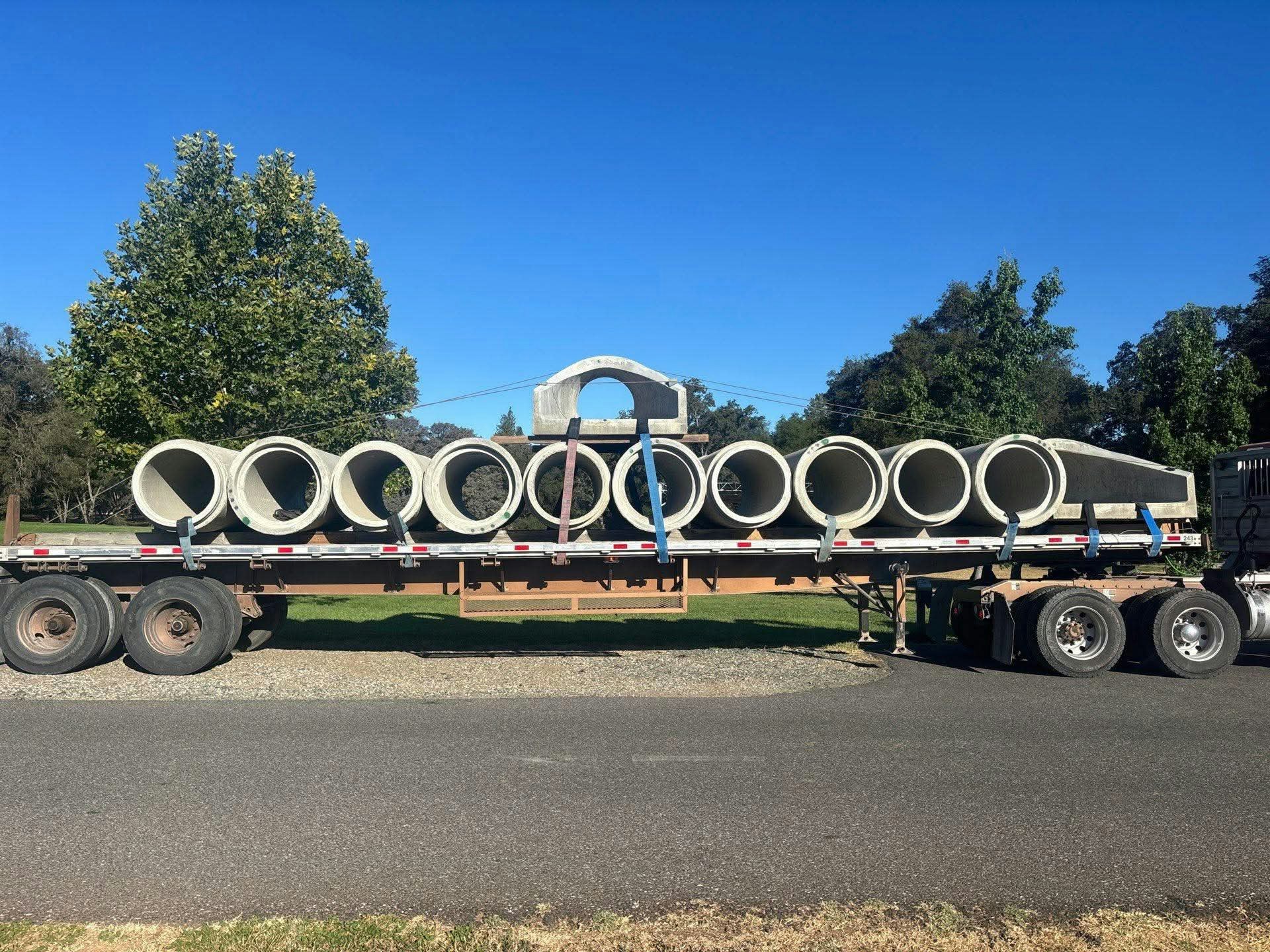 A truck carries large concrete culverts for the new Squirrel Creek crossing.
