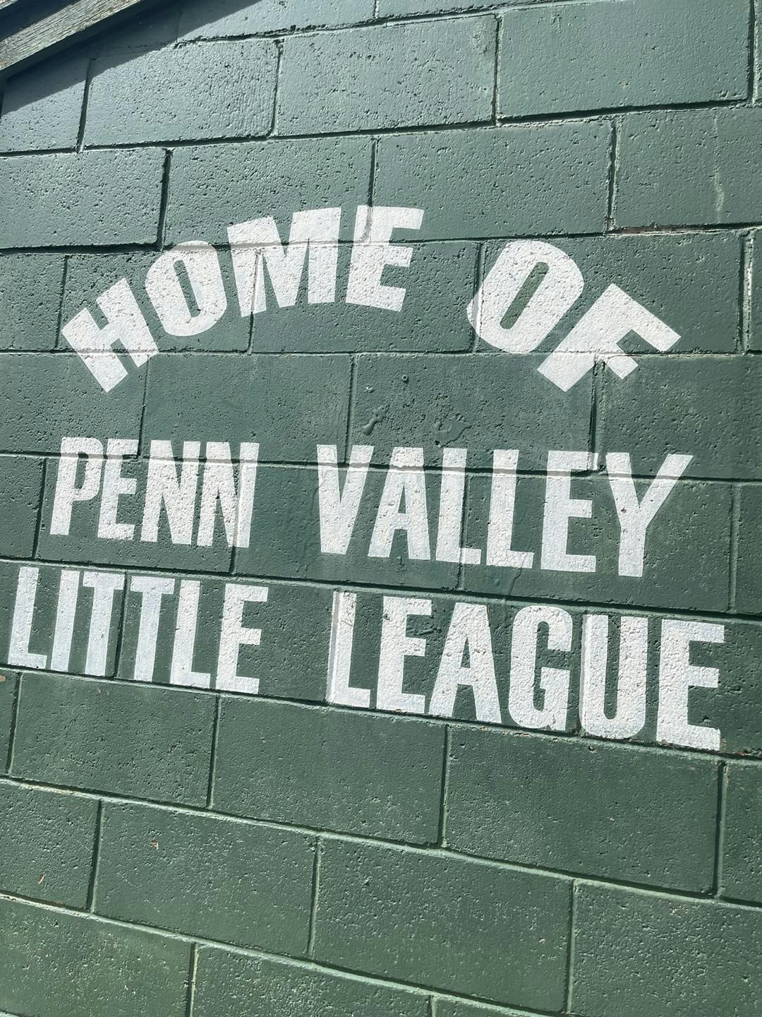 Green brick wall with "HOME OF PENN VALLEY LITTLE LEAGUE" painted in white.