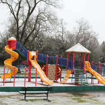Colorful playground set with slides and climbing structures on a cloudy day.