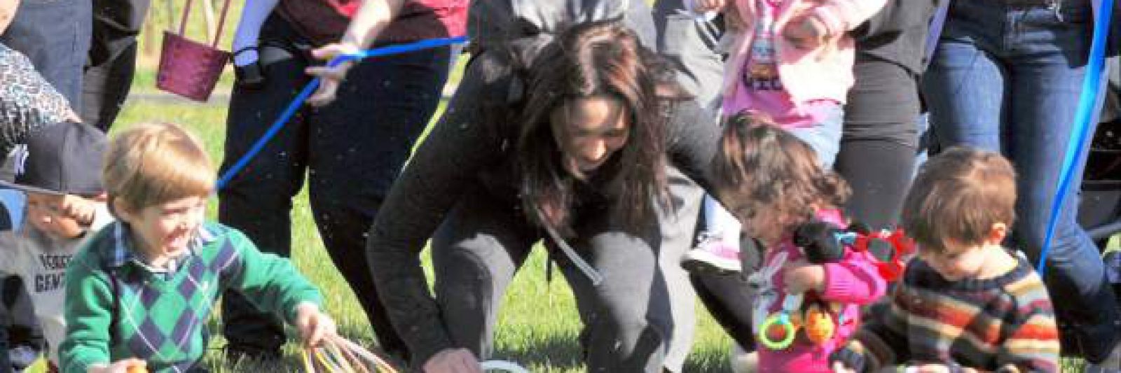 Adults and children participating in an outdoor activity, some with baskets.