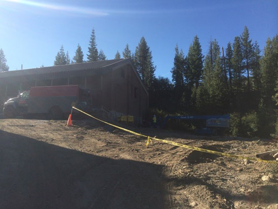 A house near a forest, construction site with caution tape and a parked truck.