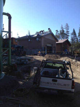 A construction site with a building, a parked pickup truck, and construction equipment.