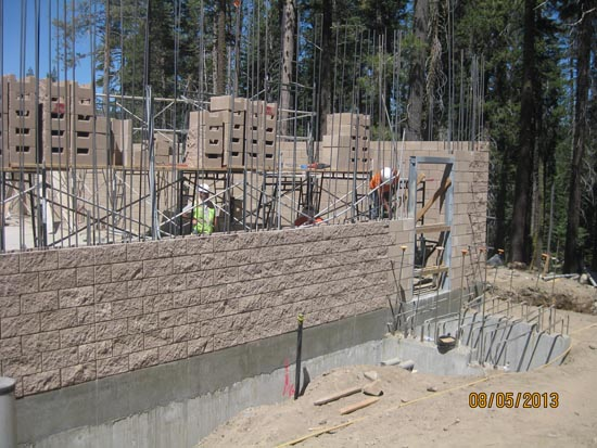 A partially constructed building with scaffolding and concrete blocks in a forested area.