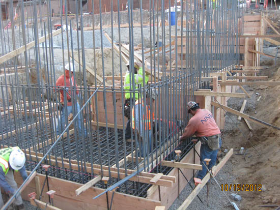 Construction workers assembling rebar for concrete foundations on a building site.