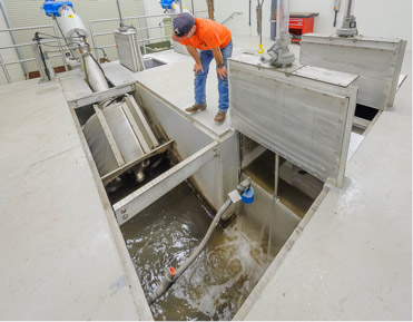 A worker observing industrial equipment, possibly a water or waste treatment facility.