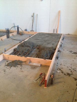 A partially filled concrete form with rebar on a construction site.