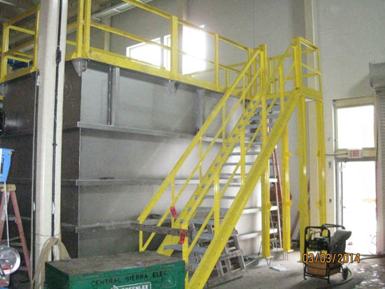 A yellow metal staircase with railings inside a warehouse or industrial setting.