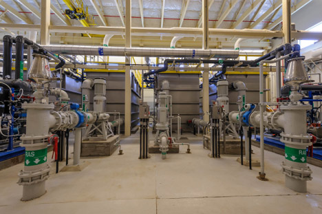Industrial room with pipes, valves, and pumps.