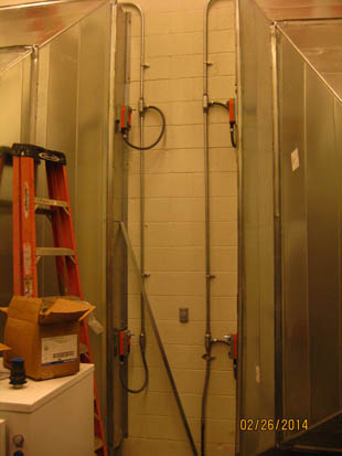 Industrial room with metal panels, pipes, a ladder, and a box on a machine.