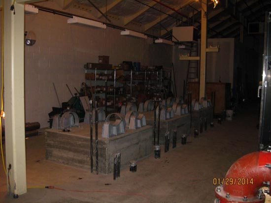 Industrial workshop with metal structures, shelves, tools, and equipment.
